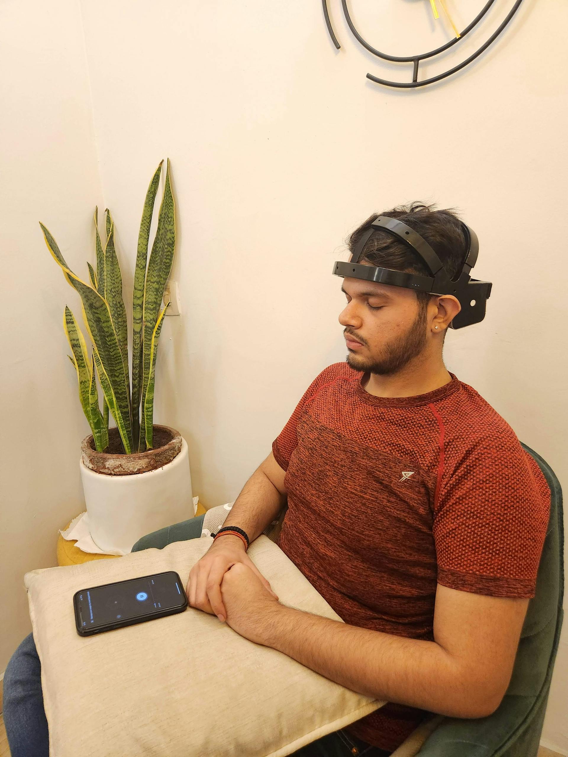 A man using an EEG headband, seated indoors, focusing on mental health and relaxation.